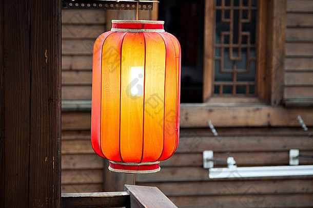 以传统的木质墙壁为背景，在柱子上悬挂红灯笼