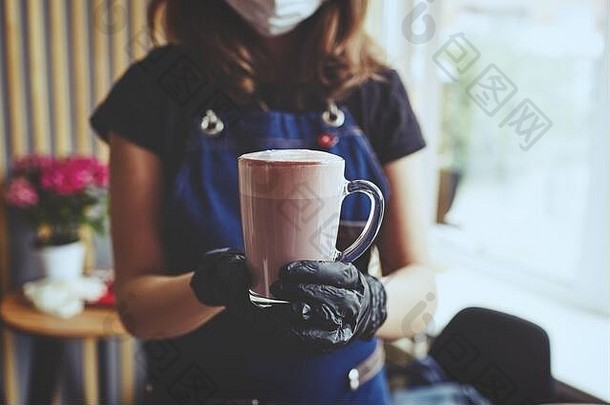 咖啡师穿脸保护面具医疗乳胶黑色的手套使粉红色的火柴拿铁牛奶酒保准备美味的喝