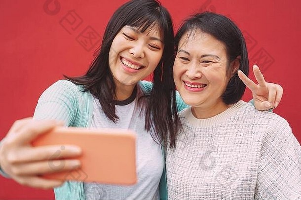 亚洲母女用手机自拍户外-快乐的中国家庭享受新潮流科技应用的乐趣