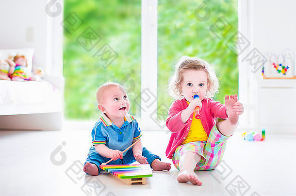 两个小孩——可爱的卷发蹒跚学步的小女孩和一个有趣的小男孩，兄弟姐妹在演奏音乐，玩<strong>木琴</strong>