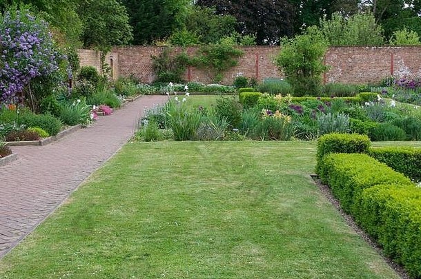 美丽的英国乡村围墙花园，有草坪和花坛