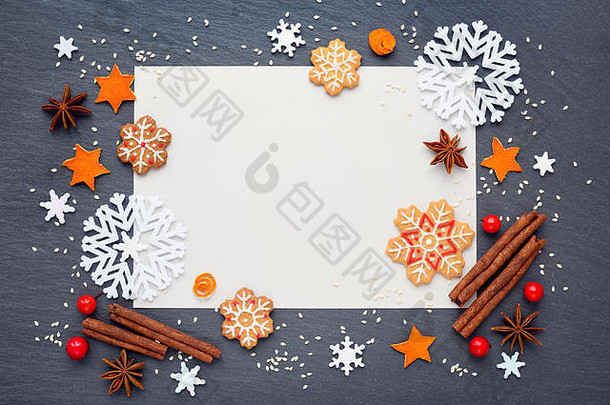 圣诞背景，姜饼饼干，雪花，香料和空白纸，祝贺你在黑暗的桌子上，俯视图