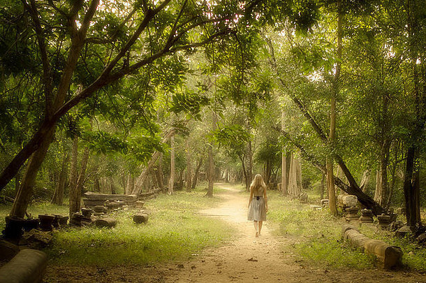 一位年轻女子走在一条神秘的小路上，走进了一片迷人的森林。