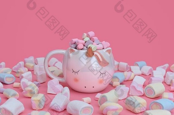 独角兽杯，粉红色背景上散布着五颜六色的棉花糖。Sweets概念中包含文本的位置。金角独角兽