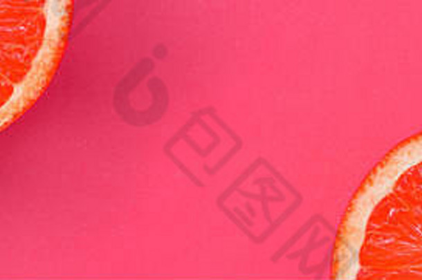 粉红色明亮背景上几片葡萄柚片的俯视图。饱和柑橘纹理图像
