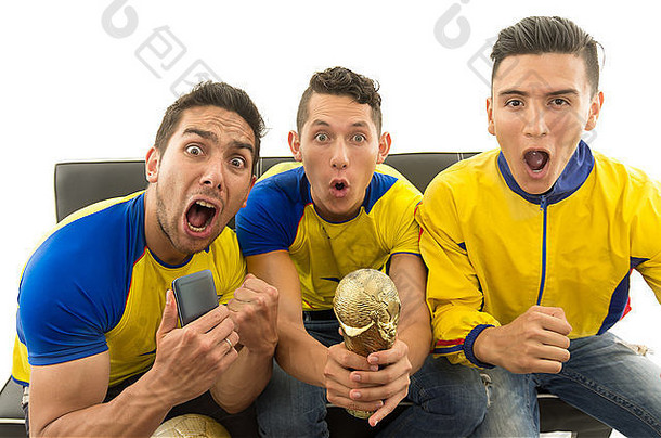 三个朋友坐在沙发上，穿着黄色运动衫，在镜头前尖叫着欢呼，背景为白色，从上方拍摄