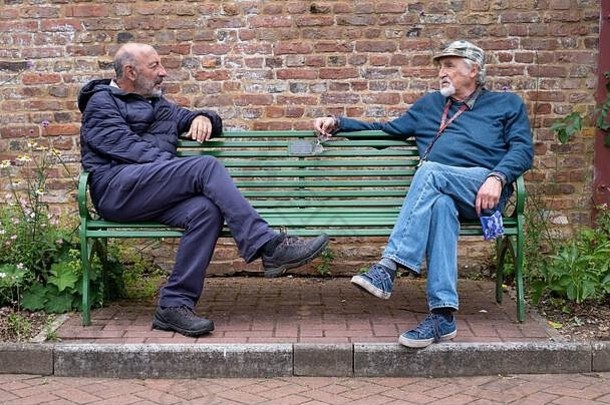 英国伦敦。2020年6月。在冠状病毒封锁期间，两名退休男子坐在公园长椅的两端，与社会保持距离。