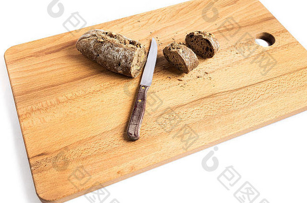 一小块全麦面包和新做的核桃，旁边放着一把刀，放在木板上