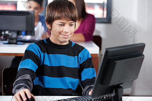男孩在教室里使用电脑时微笑