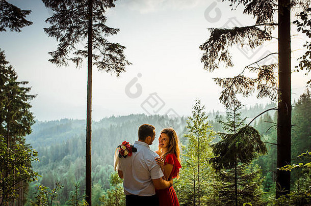 快乐夫妇爱微笑温柔拥抱森林背景绿色山日落