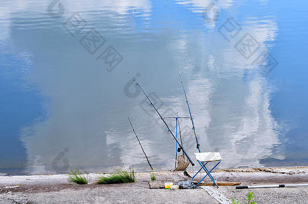 湖边有钓鱼杆和钓鱼设备的椅子