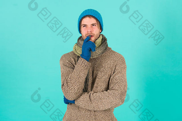 如果…怎么办。帅哥没刮胡子的家伙穿着蓝色背景的冬季配饰。冬季大减价。时髦的针织冬季帽子围巾和手套。情感表达。思考和决定。艰难的决定。