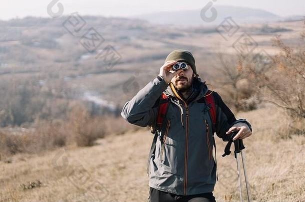 留胡子的游客使用双筒望远镜观看山景