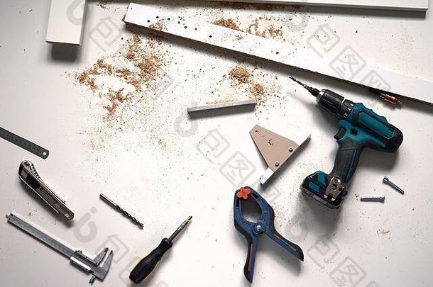 男人在家里<strong>做</strong>装修工作，用螺丝刀钻孔。木质白色背景上的一组维修工具。