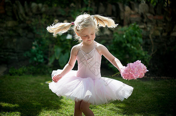 穿着粉色短裙的小女孩在花园里玩耍