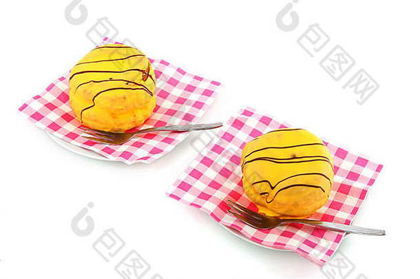 盘子上放着甜美的黄色蛋糕，上面铺着粉红色的方格餐巾