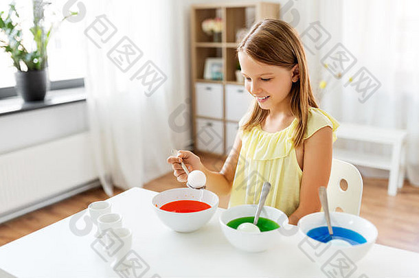 在家里用液体染料给复活节彩蛋着色的女孩