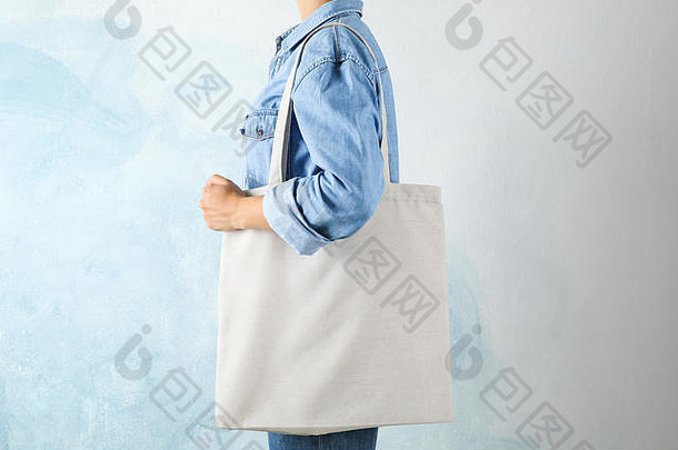 年轻的女人持有手提包袋蓝色的背景空空间