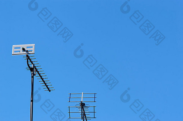 英国柴郡房屋屋顶上竖立的电视天线，背景为晴朗的蓝天