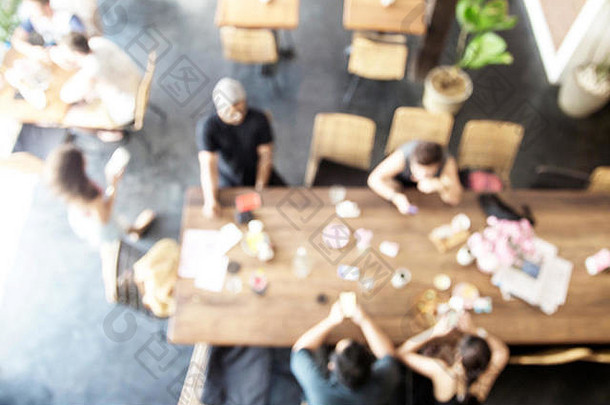 咖啡馆里人的模糊背景。阁楼式的长桌子。顶视图。团队合作理念。