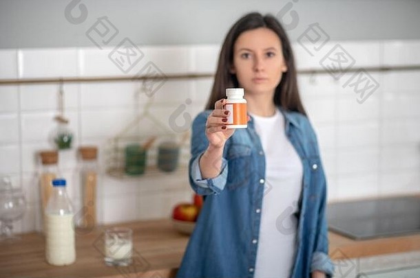 一名妇女拿着一个装有<strong>维生素</strong>药片的容器