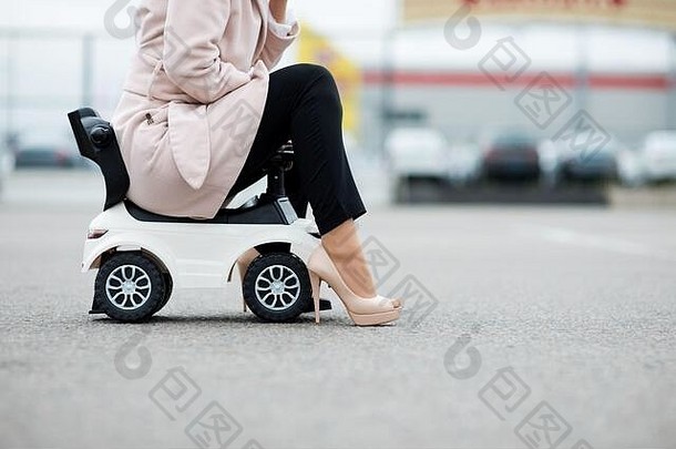 一名妇女坐在一辆婴儿车上的双腿特写镜头，这辆婴儿车正站在人行道上。拷贝空间