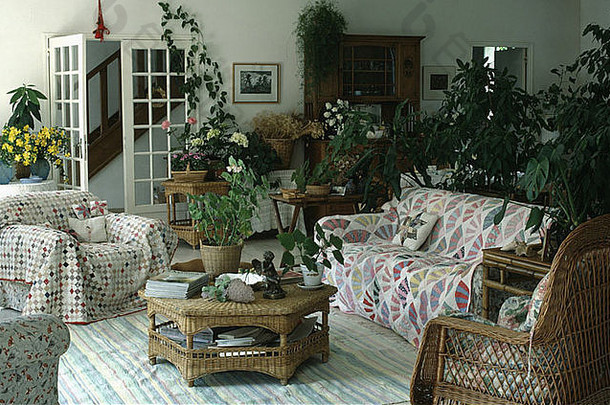 起居室的柳条桌和室内植物，长椅和扶手椅上有绗缝