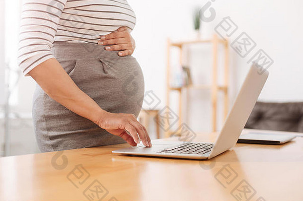 很好的孕妇在用她的笔记本电脑