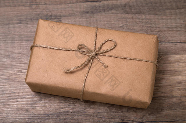 用<strong>牛皮纸</strong>包装的圣诞或新年礼品盒，旧木质<strong>背景</strong>上有空白礼品标签。