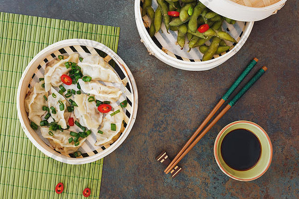 流淌的饺子和毛豆在竹蒸笼里加盐加热食用。顶视图，空白区域