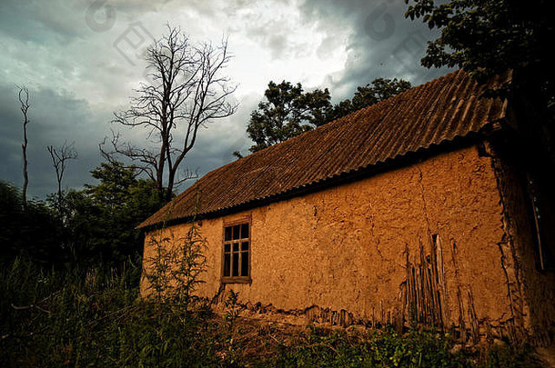 日落时森林边缘的老乌克兰村舍（泥屋）