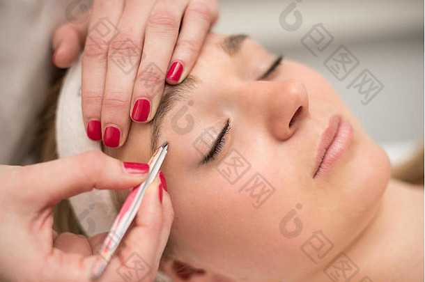 美容院美容师用镊子拔眉毛。