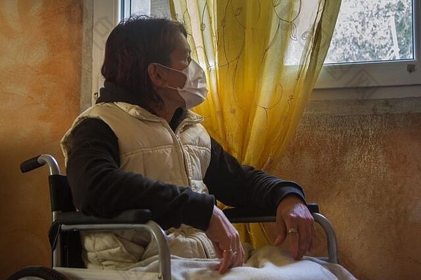 上了年纪的女人病人卫生面具口无聊隔离轮椅窗口