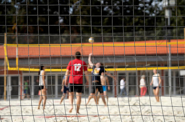 一群年轻的朋友打沙滩排球，夏日，选择焦点。模糊的背景，健康的生活方式概念