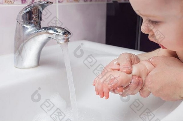 孩子在水槽里洗手。从水龙头喷出的水。用水消毒双手。病毒防护。洗手、卫生的概念。冠状病毒c