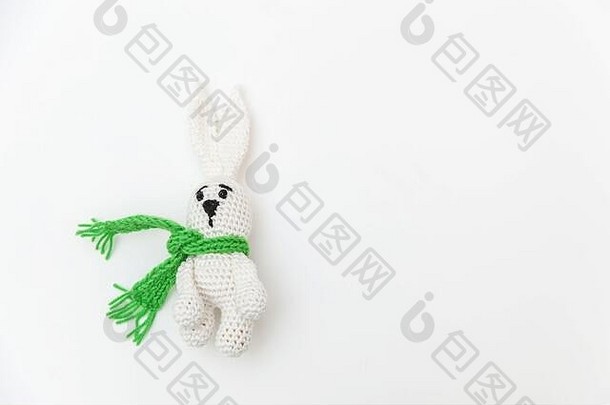 简单简约的设计，白色背景上隔离着绿色围巾的玩具兔子。儿童保育材料家庭观念。平面俯视图空间
