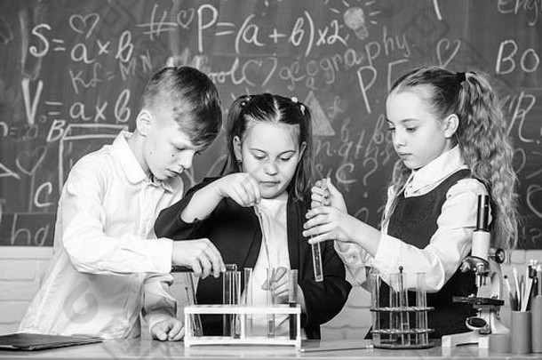 小孩子们在学校实验室学习化学。学生们用显微镜做生物实验。实验室显微镜。儿童节。化学显微镜。实验室里的小孩。受到激励努力工作。
