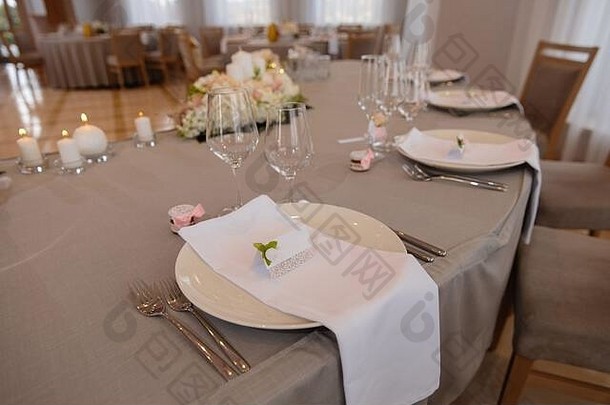 在东欧波罗的海-里加-拉脱维亚举行的一场婚礼上，白色大厅里的餐桌上摆着食物——比格、奶油和带有姓名标志的粉红色