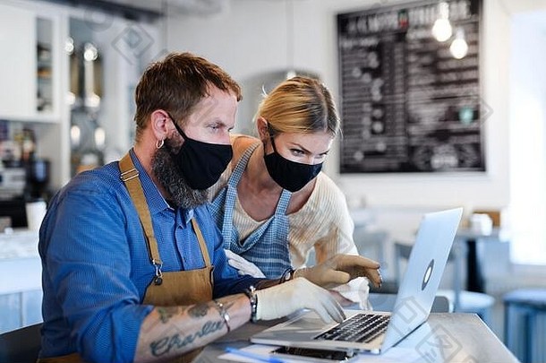 咖啡店老板带着口罩，封锁，隔离，冠状病毒，恢复正常的概念。