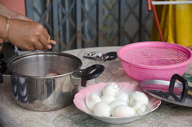 一名<strong>泰国</strong>妇女正在剥煮鸡蛋，准备烹调肉汁炖猪肉