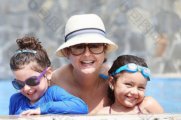 快乐的妈妈和她的孩子们在游泳池里