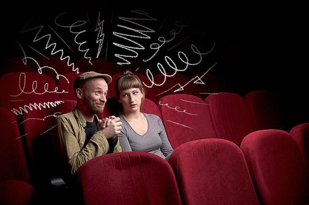 一对年轻可爱的情侣坐在电影院里，一边吃着爆米花一边看<strong>涂鸦图片</strong>的电影