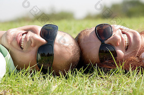 一对年轻夫妇躺在草地上微笑着