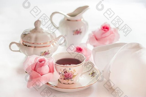 一套花卉玫瑰图案精美瓷器茶具，配有茶壶、糖壶、奶精和茶杯。