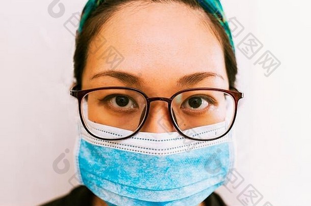 冠状病毒主题。戴眼镜的亚洲妇女戴着口罩保护自己不受感染