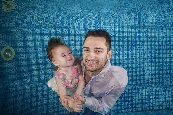 爸爸和女儿在游泳池里潜入水下