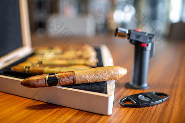 室内木桌上装有打火机的豪华雪茄的特写镜头