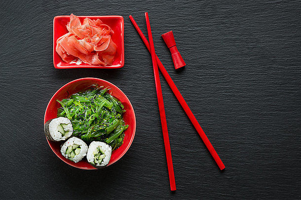 石板桌上放着生姜和海鲜沙拉的寿司卷。