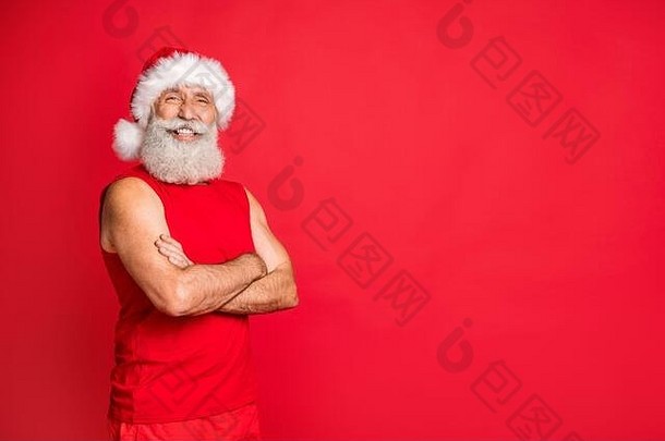 转过来的照片是戴着帽子的快乐圣诞老人，真正的运动教练交叉<strong>双</strong>手，微笑着戴着<strong>红色背景</strong>下的运动帽