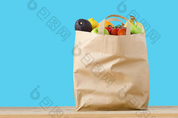 棕色（的）纸购物袋填满前品种水果光木<strong>表面</strong>孤立的绿松石蓝色的背景